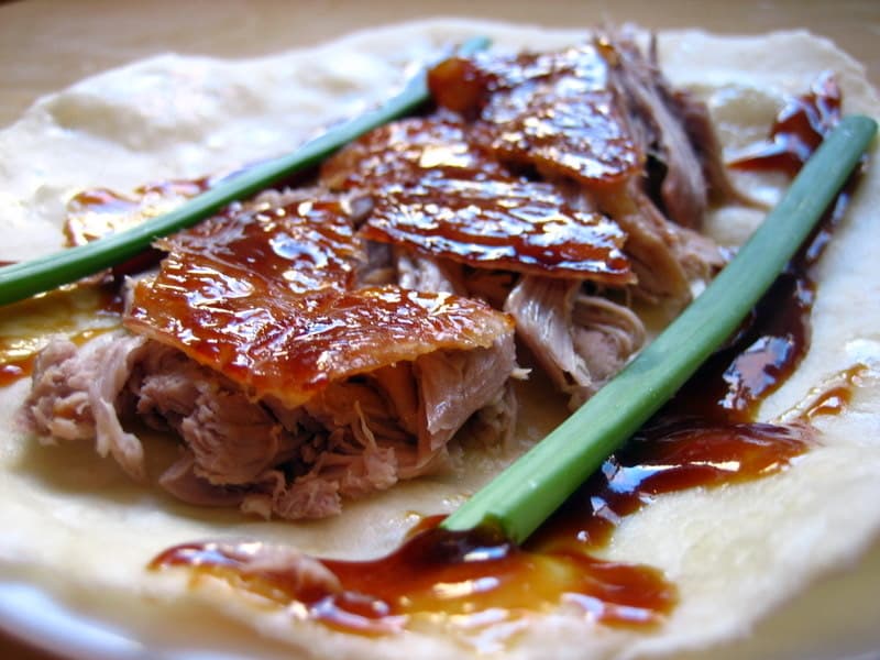 The classic wrap is part technique and part personal preference: duck, sauce, scallion, cucumber, and restraint.