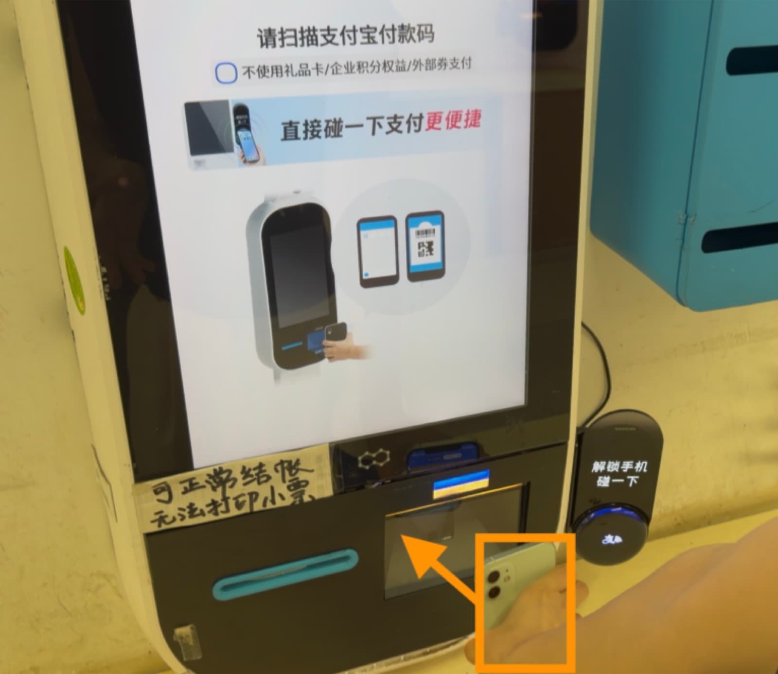 Self-checkout kiosk with a phone held to the QR scanning window