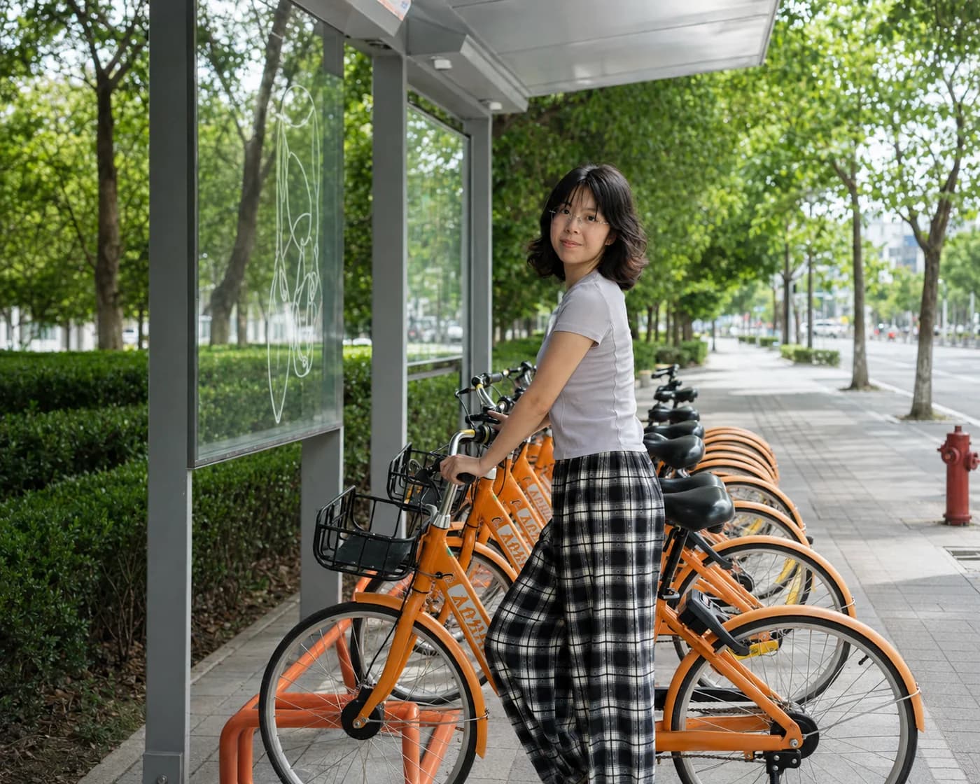 Yadi beside a row of shared bicycles outdoors