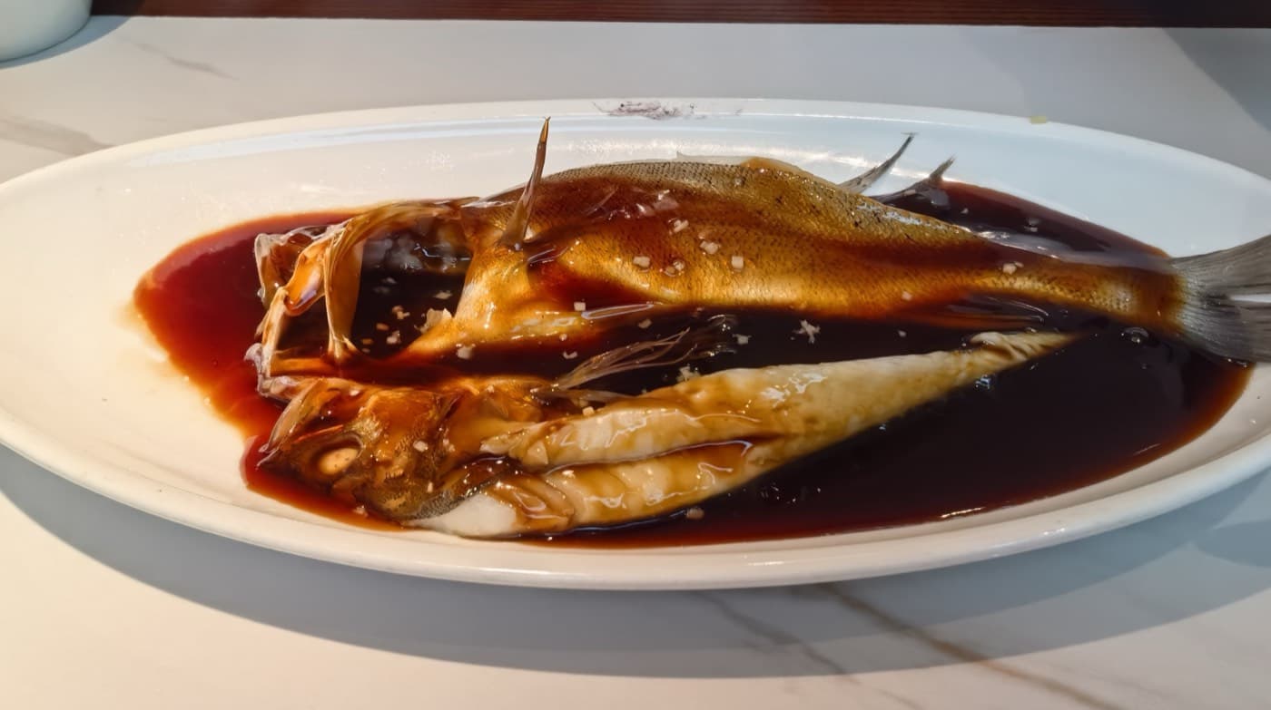 The dish is about soft fish and vinegar gravy rather than crunch, char, or fillet-style convenience.